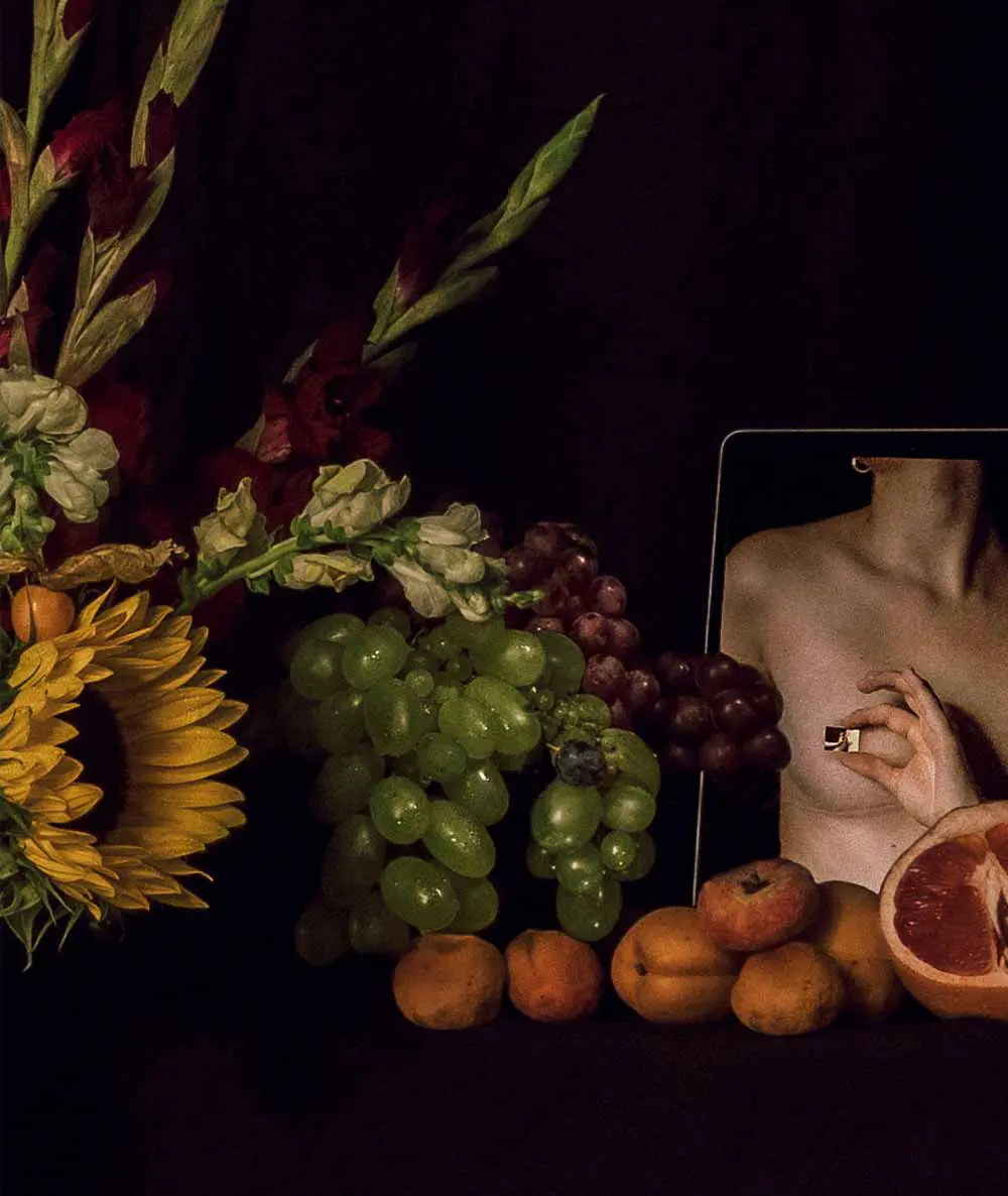
                   Stillleben mit Obst und Blumen, neben einem Tablet, das ein Frau mit Ring in den Fingern zeigt. 
                   